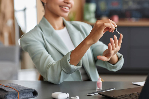 Мінімальний крупний план усміхненої чорної бізнес-леді, що робить манікюр на робочому місці в офісі, копіювання простору - Фото, зображення