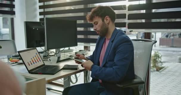 Engagé dans un appel téléphonique, un travailleur masculin tourne sur sa chaise au bureau, ajoutant une touche ludique à la conversation. - Séquence, vidéo