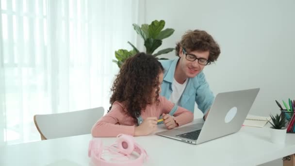 Happy father pointing at laptop screen while explain engineering prompt to african american cute child while sitting at table with computer and headphone. Dad learning generated AI together. Pedagogy. - Footage, Video