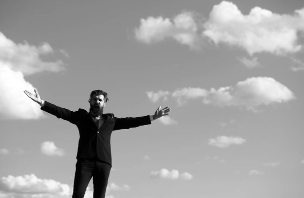 Man in suit raising hand on sky background. Freedom adventure and business victory concept. Success business and freedom - 写真・画像