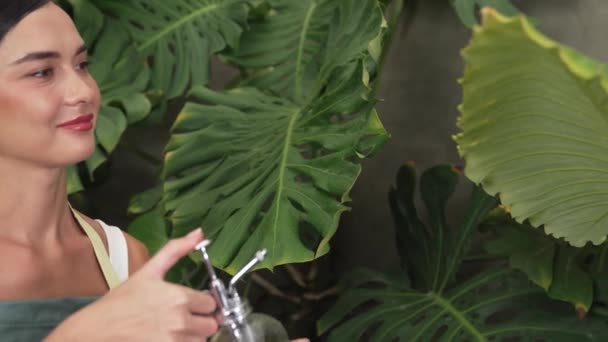 Молода жінка садівник з ніжним поливом тропічної рослини в мінімалістичному архітектурному бетонному стилі літній екзотичний сад листя рослин, садівництво для екологічного способу життя. Блайт - Кадри, відео