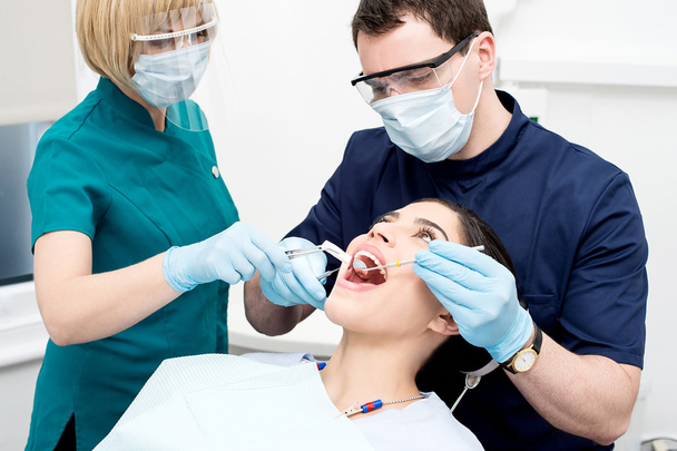 Dentist treat the female patient - Fotoğraf, Görsel