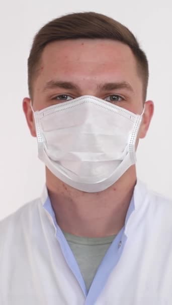 Un hombre que usa equipo de protección personal, incluyendo una máscara médica blanca en su cara, para proteger su frente, cejas, pestañas, mandíbula y cuerpo humano - Imágenes, Vídeo