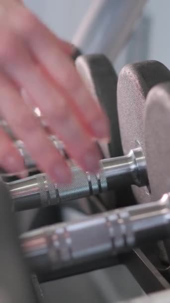 A rack of dumbbells is neatly organized in the gym building, made of metal and placed next to the automotive exterior event. The engineering of each dumbbell ensures durability - Footage, Video