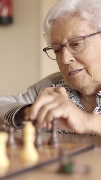 Slow motion video van twee oudere vrienden die schaken bordspel spelen in een geriatrische - Video