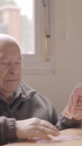 Видео медленного движения некоторых пожилых людей и карегивера, играющих в карты вместе в доме престарелых - Кадры, видео