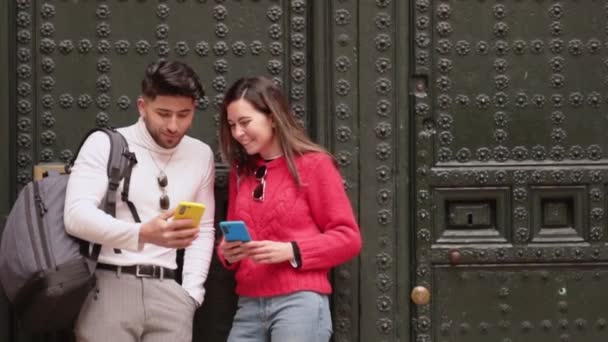 Dos amigos mirando memes con sus celulares y riéndose por una pared. Copiar espacio. Imágenes FullHD de alta calidad - Metraje, vídeo