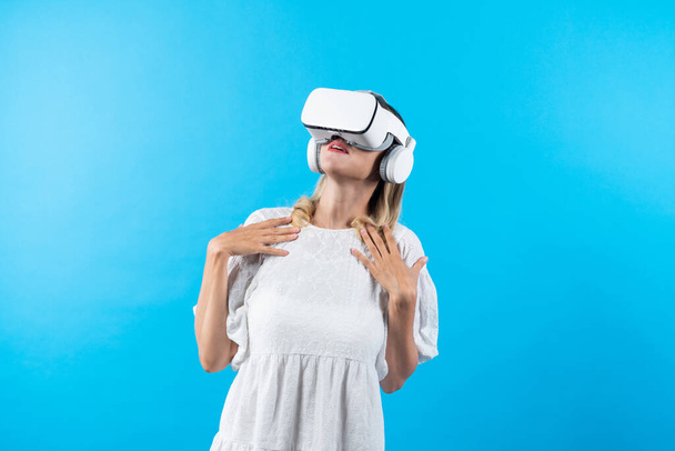 Skilled girl in pajamas excited with metaverse by using VR goggle at background. Caucasian woman surprised while looking around at futuristic view looking though visual reality goggles. Contraption. - Photo, Image