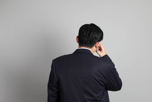 Asijský podnikatel s formální oblečený s gestem myšlení na šedém pozadí. - Fotografie, Obrázek