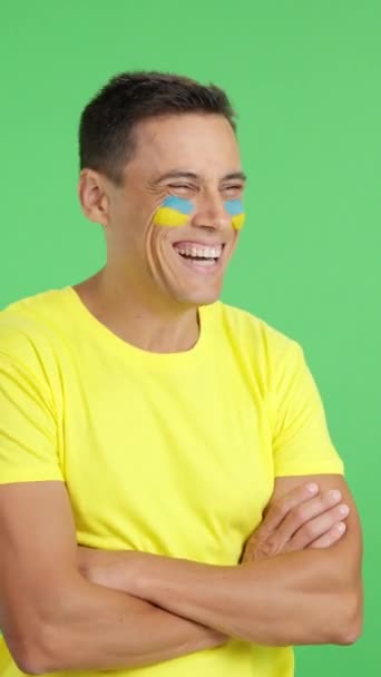 Vidéo en studio avec chroma d'un homme heureux avec drapeau ukrainien peint sur le visage regardant loin de l'espace de copie en blanc - Séquence, vidéo