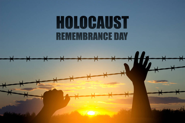 Holocaust-Gedenktag. Handsilhouette mit Stacheldraht bei Sonnenuntergang - Foto, Bild