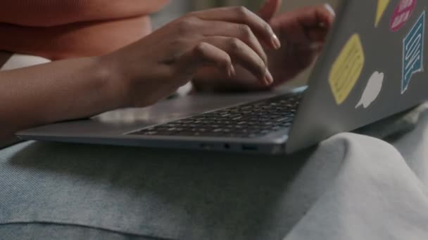 Поднятие среднего роста молодой чернокожей женщины, сидящей за ноутбуком во время учебы или работы из дома - Кадры, видео