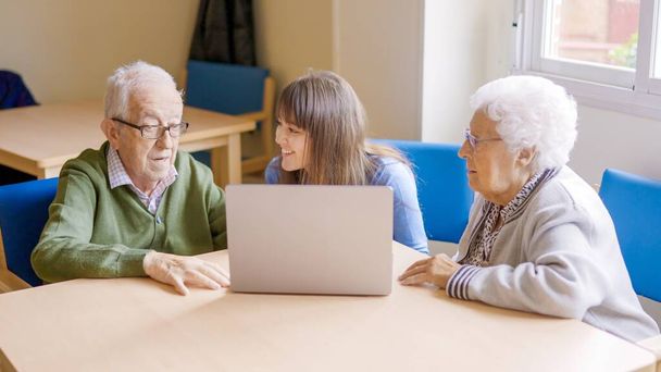 Внучка помогает бабушке и дедушке пользоваться ноутбуком в престарелых - Фото, изображение
