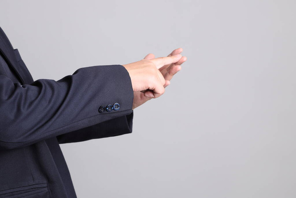 De Aziatische zakenman met formele gekleed met gebaar van tellen aantal op de grijze achtergrond. - Foto, afbeelding