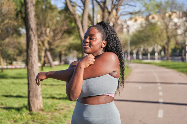 Фітнес, афроамериканська жінка розтягує руки, щоб розігріти тіло або розслабити м'язи для тренувань. Оздоровчий, фокус або здоровий спортсмен готовий почати тренування або фізичні вправи - Фото, зображення