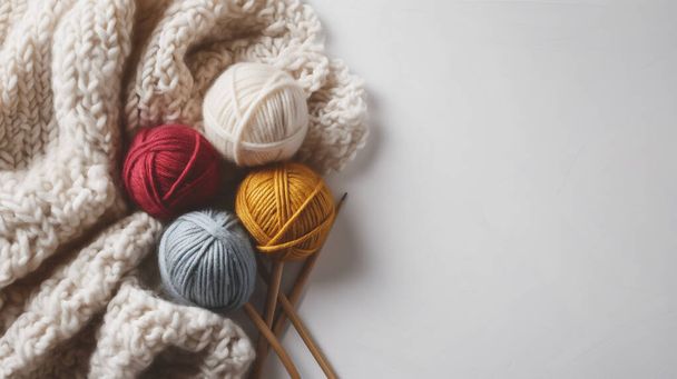 Colorful yarn balls with knitting needles and a knitted blanket on white background. - Photo, Image
