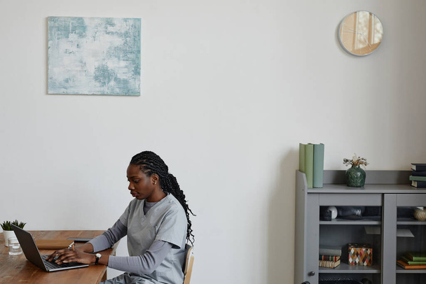 Portrait de jeune femme noire comme infirmière utilisant un ordinateur portable au bureau, espace de copie - Photo, image