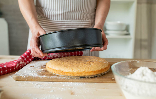 Poistaminen kakku pohja leivinpannulla tai kakku pannulla naisten käsissä keittiössä. - Valokuva, kuva