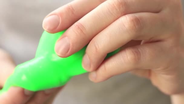 Dívka hnětá zelený sliz. Detailní záběr ženských rukou natahujících jasně zelený sliz. Antistresová hračka pro relaxaci a klid. Zábavná smyslová aktivita. Koncept hračkářství - Záběry, video