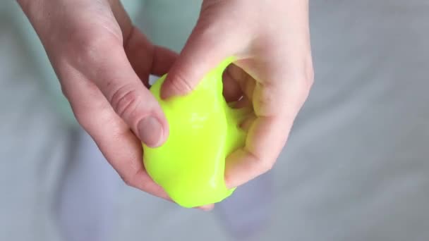 The girl kneads the yellow mucus. Woman's hands stretch bright yellow slime close-up. An anti-stress toy for relaxation, a way to take your mind off work or school. A fun sensory activity - Footage, Video