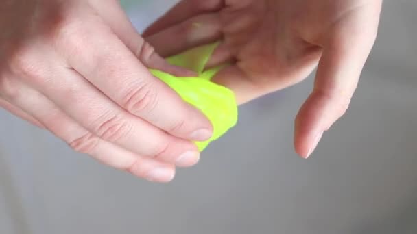 Girl kneads the yellow mucus. Woman's hands stretch bright yellow slime close-up. An anti-stress toy for relaxation, a way to take your mind off work or school. A fun sensory activity - Footage, Video