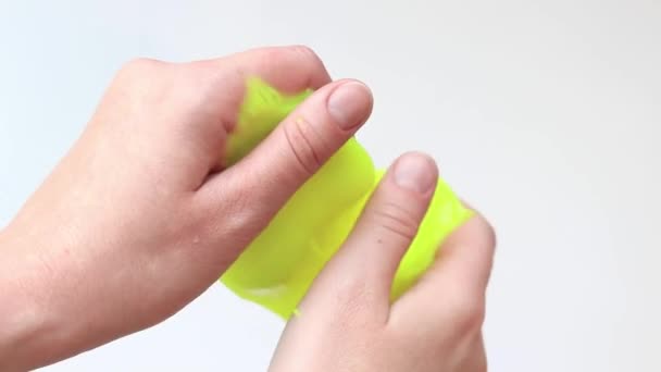 The girl kneads the yellow mucus. Female hands stretch bright yellow slime close-up, white background. Anti-stress toy for relaxation. A fun sensory activity. Toy store concept - Footage, Video