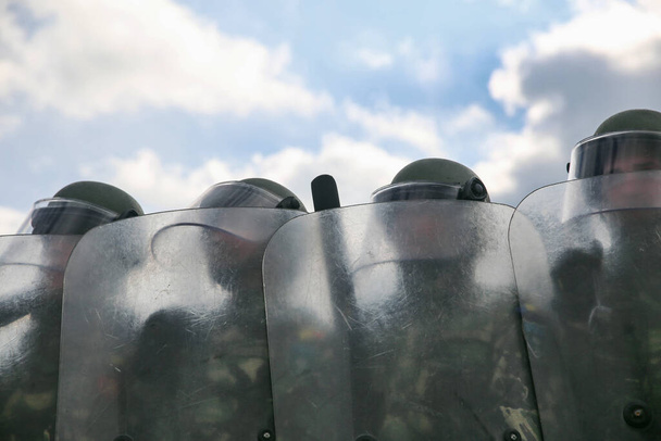 Policja zamieszek tworząca linię niosącą tarcze perspektywiczne i noszące kaski - Zdjęcie, obraz