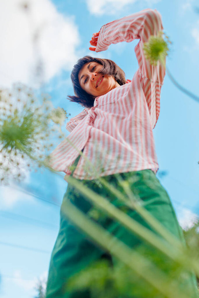 fille dans une chemise rose se déplace dans le ciel bleu. Portrait d'une jeune fille jouissant de la nature à l'extérieur dans un champ fleuri. Le visage d'une belle jeune fille en gros plan. - Photo, image