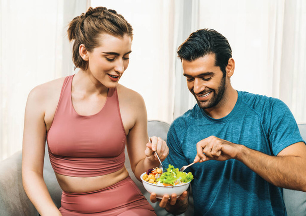 Spor giyim kuşamında bir kase meyve ve sebzeli sağlıklı spor ve vejetaryen çift. Sağlıklı beslenme ve spor için vejetaryen yaşam tarzı ev konseptinde vücut fiziği. - Fotoğraf, Görsel