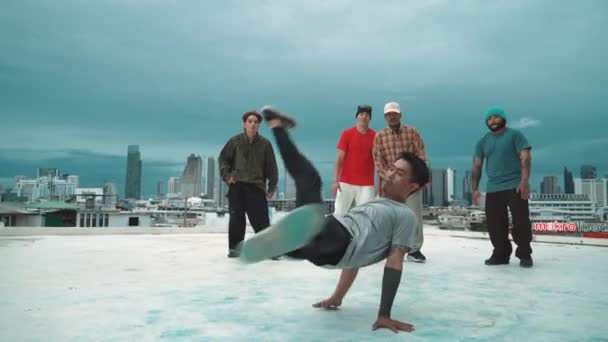 Hispanische Hipster tanzen umgeben von multikulturellen Freunden bei Stadtblick mit blauem Himmel. Eine Gruppe von Streetdancern tritt auf dem Dach auf. Aktiv, lustig, fröhliche Atmosphäre. Outdoor-Sport 2024. hiphop. - Filmmaterial, Video