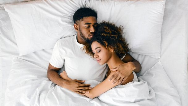 トップ ビューのベッドで一緒に寝ている若いアフリカ系アメリカ人のカップルをコピー スペース - 写真・画像