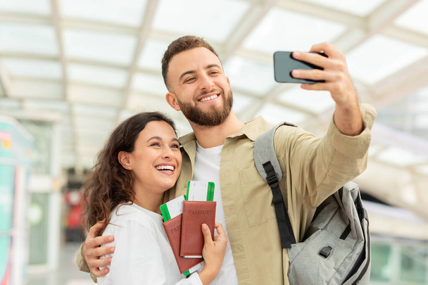 Hombre y mujer tomando selfie en el teléfono inteligente en el aeropuerto, Pareja feliz captura de fotos mientras esperan su vuelo, Disfrutando de viajar juntos, Primer plano - Foto, imagen