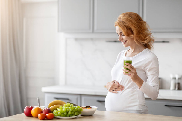 Captured in a modern european kitchen, a pregnant lady emphasizes good nutrition with a variety of healthy foods prepared on the counter - Photo, Image