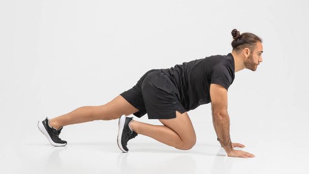 Determined man in a black outfit performing push-ups with an emphasis on form and strength over a clear background - Photo, Image