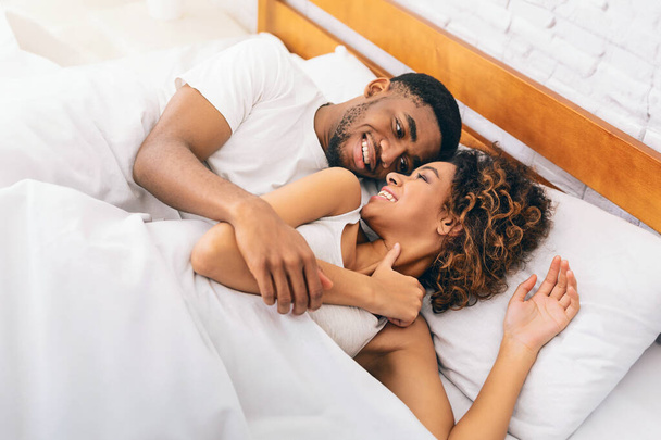 Щасливого ранку разом. Тисячолітній афро-американська пара посміхається один одному в ліжку, вільний простір
 - Фото, зображення