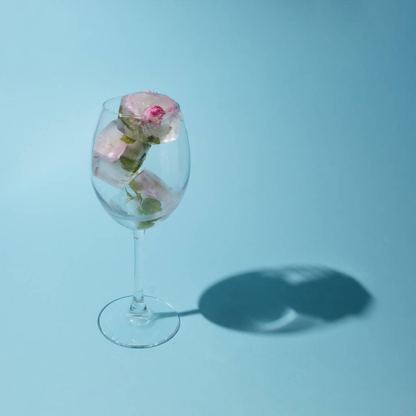 Krásné malé růžové květy v průhledném skle na modrém pozadí s kopírovacím prostorem - Fotografie, Obrázek