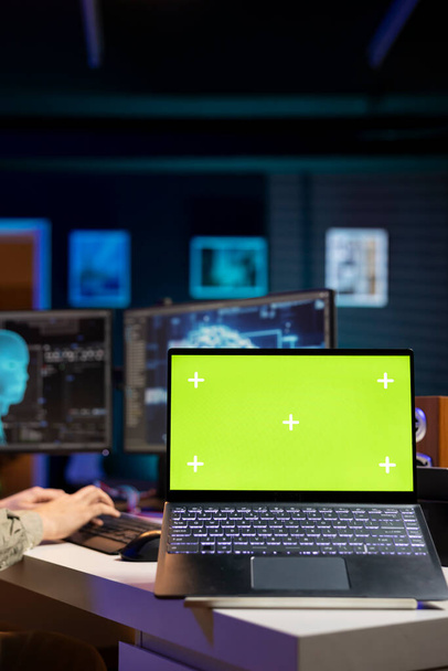 Сосредоточьтесь на ноутбуке с зеленым экраном, используемом разработчиком для обновления алгоритма машинного обучения искусственного интеллекта. Закрытие IT-эксперта в квартире с помощью программирования для обновления AI на макете ноутбука - Фото, изображение
