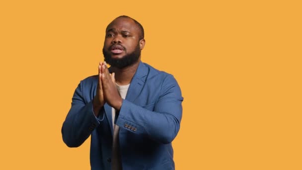 Amical homme afro-américain met la main ensemble dans le geste d'excuses, demandant pardon. Apologétique BIPOC homme faisant geste désolé, demandant pardon, isolé sur fond de studio, caméra A - Séquence, vidéo