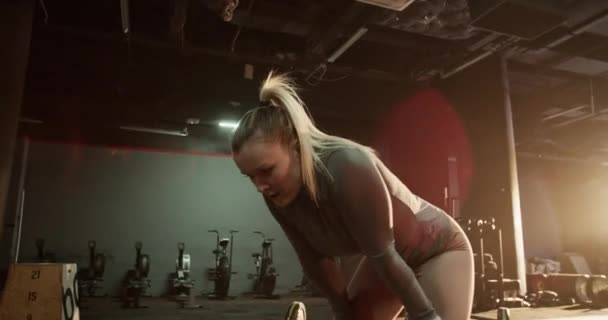 Urheilullinen nuori nainen activewear nojaten kädet polvillaan kun tauko jälkeen intensiivinen harjoitus kuntosalilla - Materiaali, video