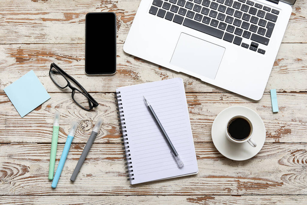 Laptop, Tasse Kaffee und Schreibwaren auf beigem Holztisch - Foto, Bild
