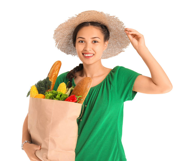 Mooie jonge Aziatische vrouw holding papieren zak met verse producten op witte achtergrond - Foto, afbeelding