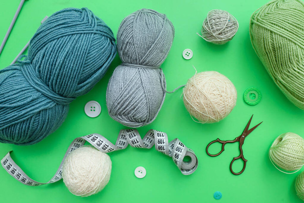 Balles de fils, aiguilles à tricoter et ruban à mesurer sur fond vert - Photo, image