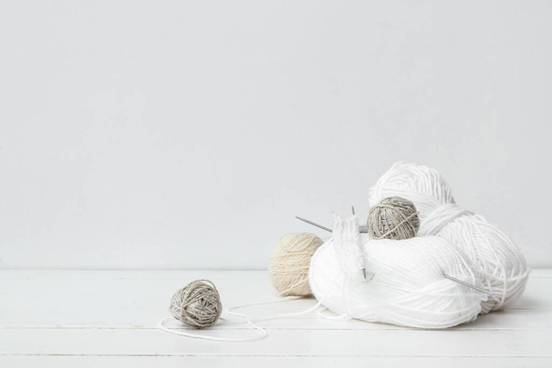 Palle di filato e ferri da maglia su tavolo di legno bianco - Foto, immagini