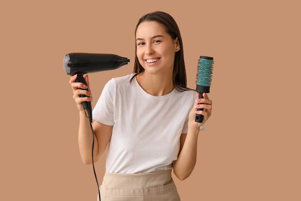 Peluquería femenina con secador y cepillo sobre fondo marrón - Foto, imagen