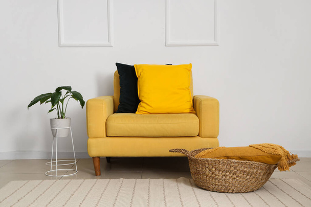 Yumuşak yastıklı sarı koltuk ve beyaz duvarın yanındaki bitki örtüsü. - Fotoğraf, Görsel