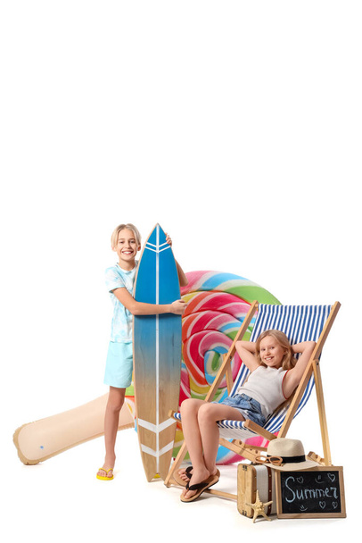Słodkie małe dzieci z nadmuchiwanym materacem, deską surfingową, leżakiem i akcesoriami plażowymi na białym tle - Zdjęcie, obraz