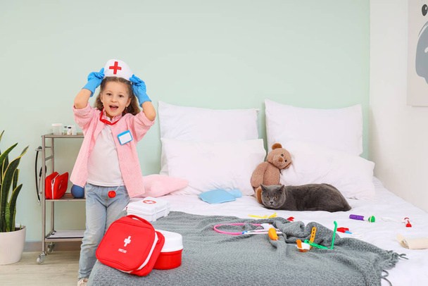 Cute little girl with first aid kits and British cat at home - Photo, Image
