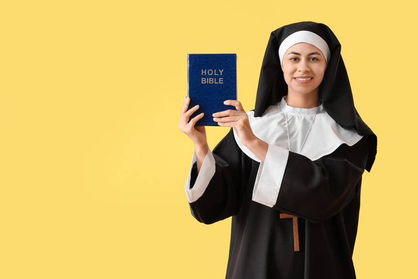 Mladá jeptiška s biblí na žlutém pozadí - Fotografie, Obrázek