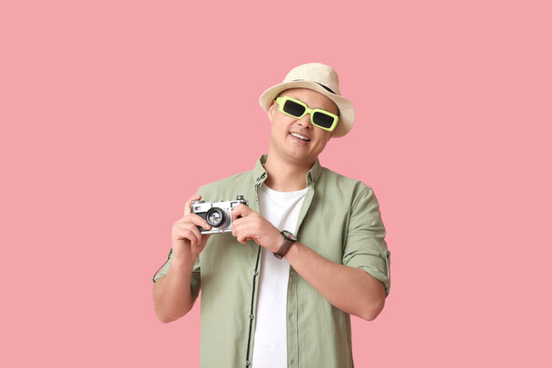 Mladý muž turista s fotoaparátem na růžovém pozadí - Fotografie, Obrázek