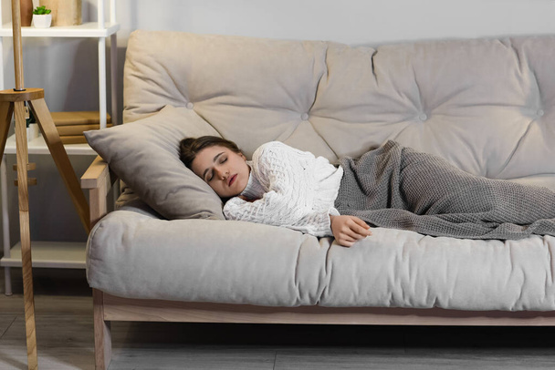 Giovane donna che dorme sul divano a casa la sera - Foto, immagini